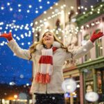 Girl in standing in snow and with lights around.